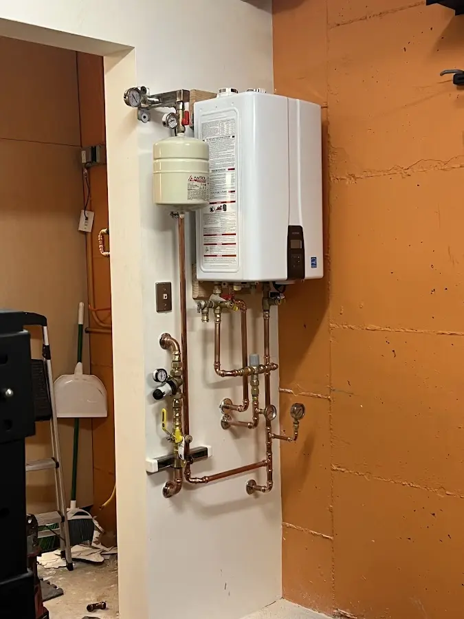 Plumbing technician inspecting water heater connections in New Bremen